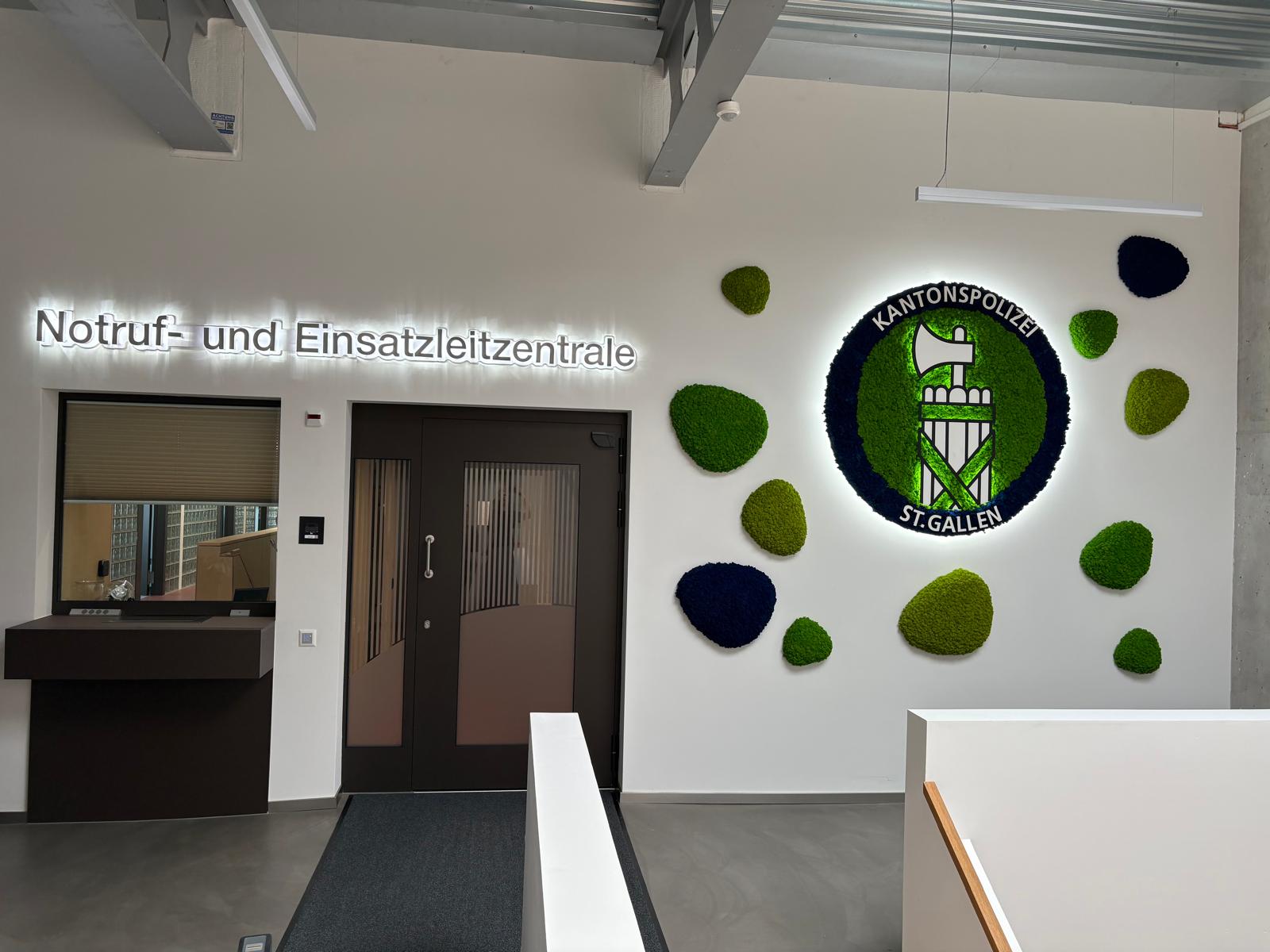 Firmenlogo aus Moos mit beleuchteter Umrandung im Empfang der Kantonspolizei St. Gallen